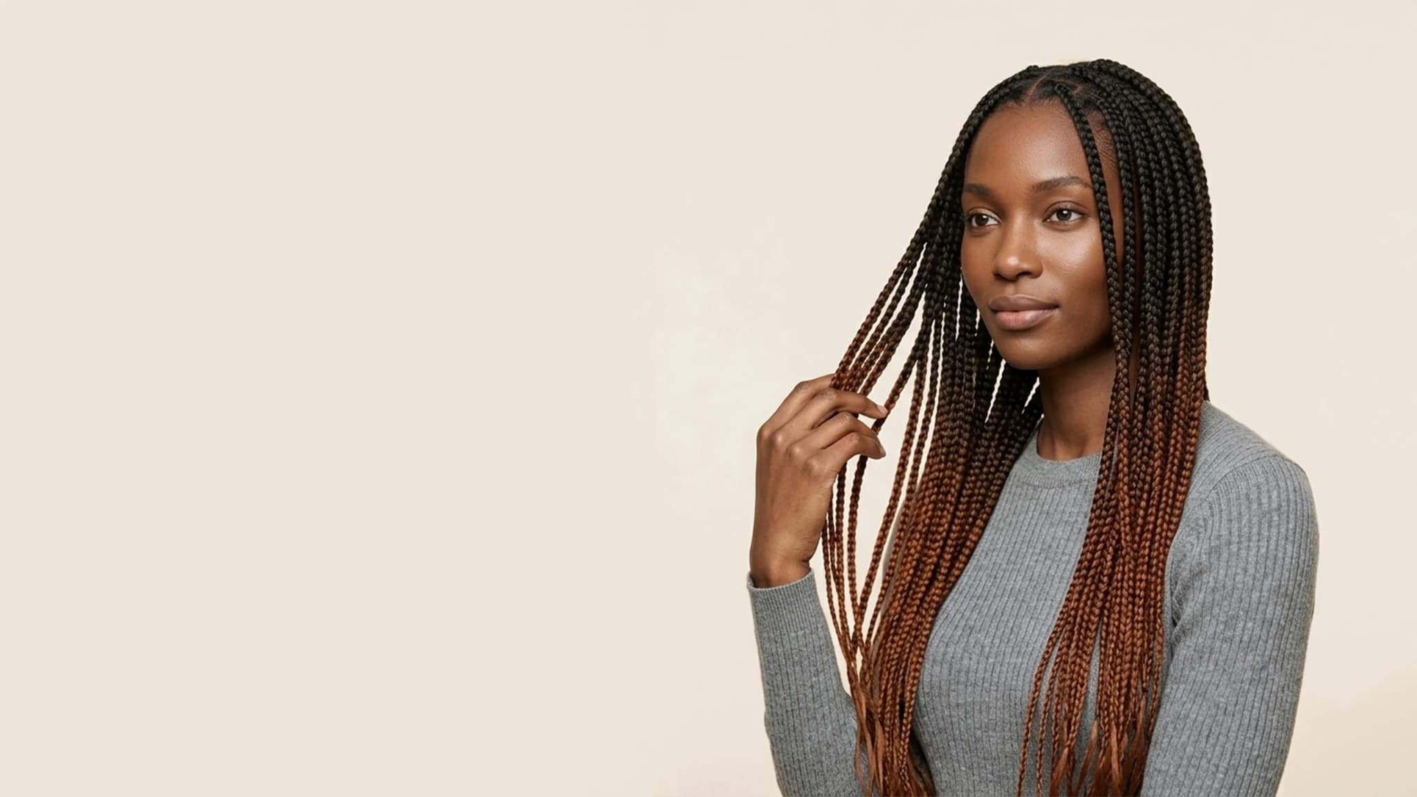 Woman with long knotless box braids in an off black to auburn ombré