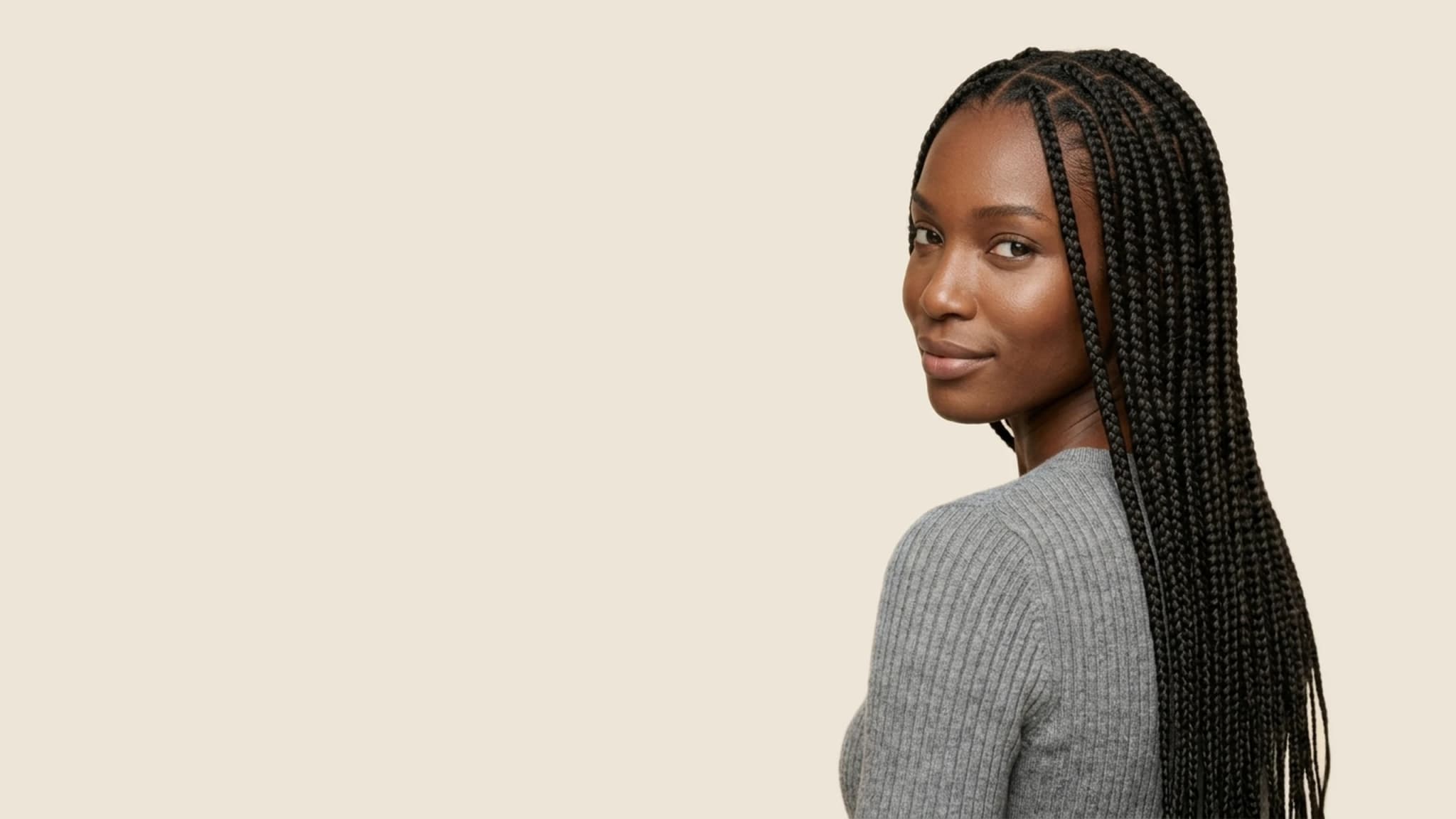 Woman with long knotless braids looking back over her shoulder