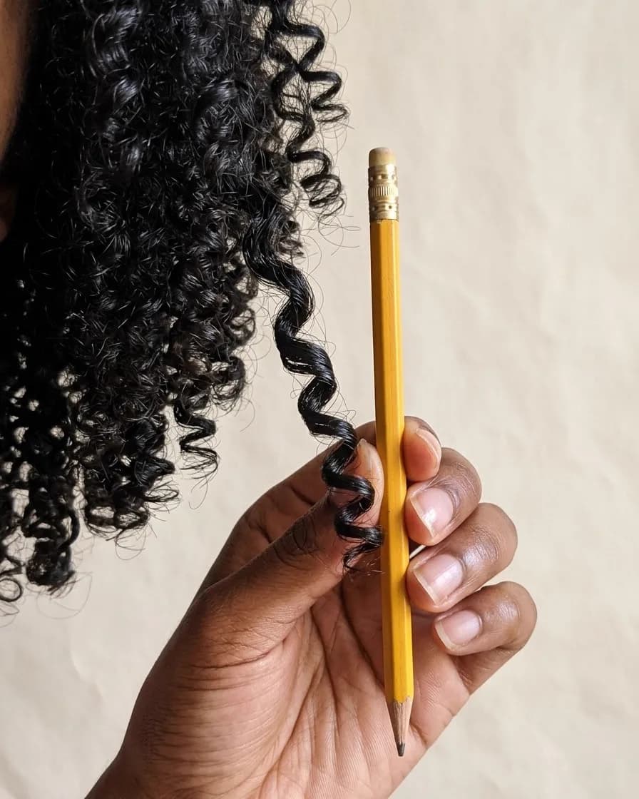 A 3C curl held beside a pencil, the same width